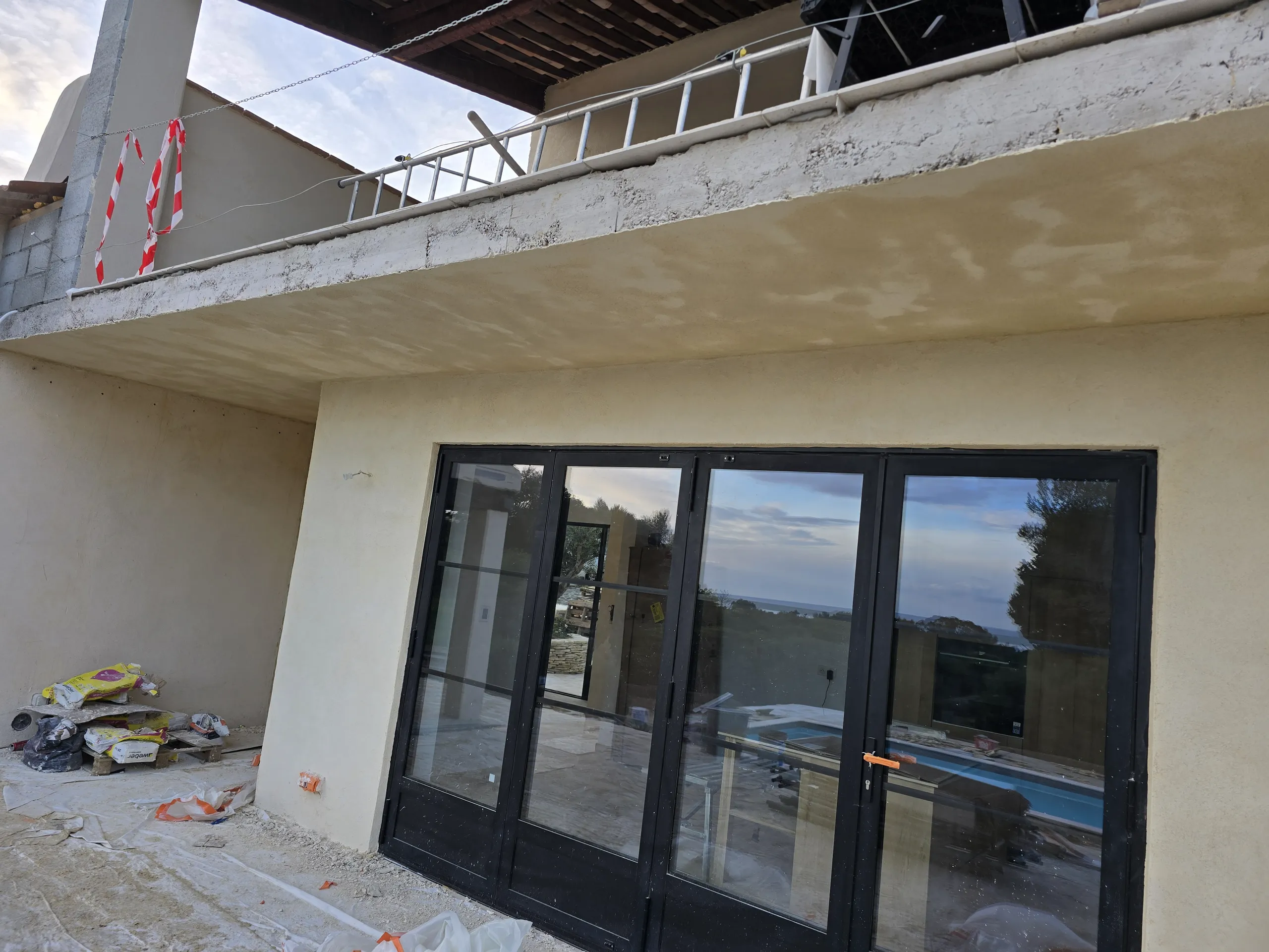 Rénovation de façade d'une maison avec balcon en cours, matériaux et outils visibles