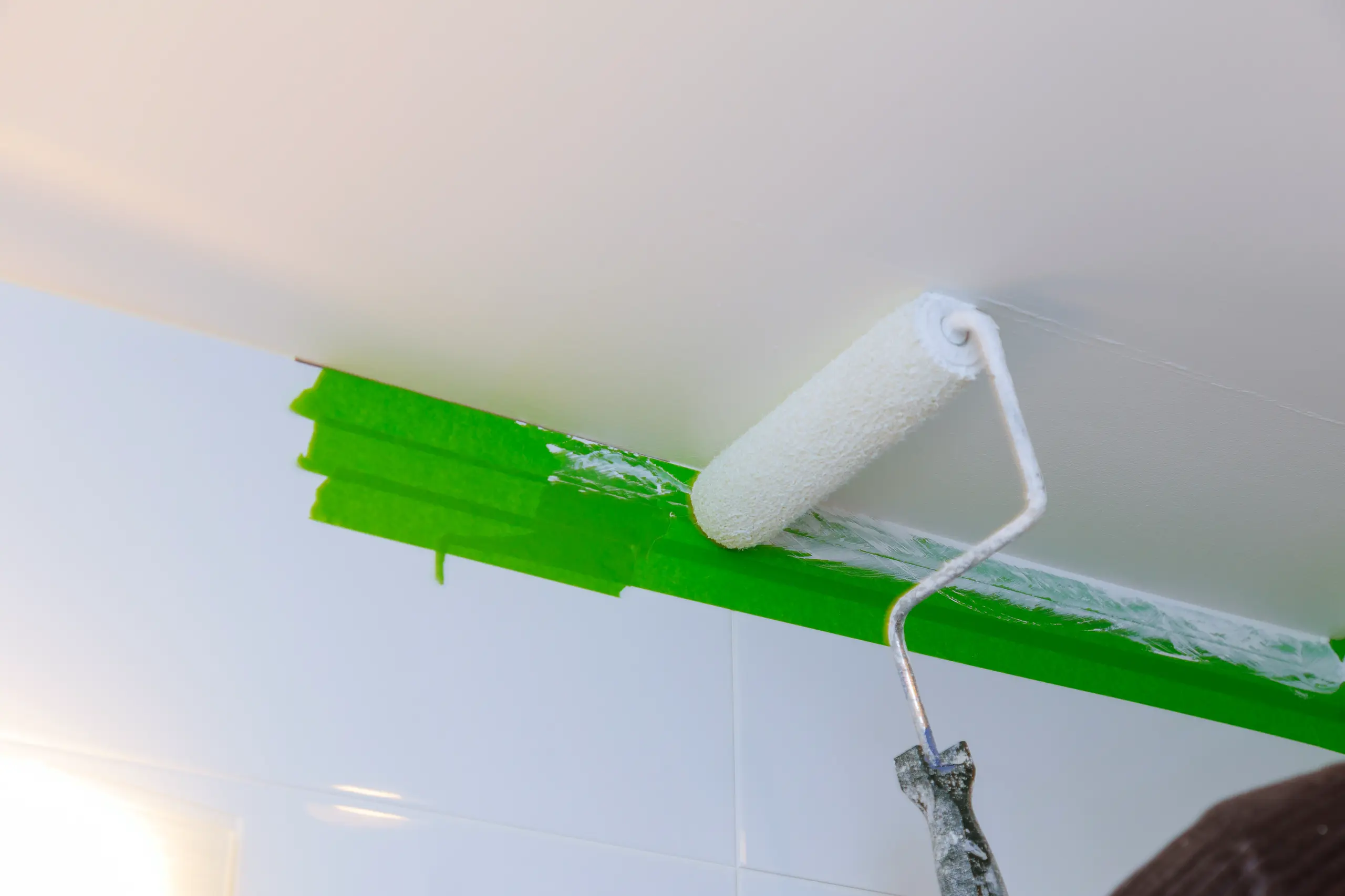 Applicateur de peinture posant un rouleau sur le plafond dans une salle de bain