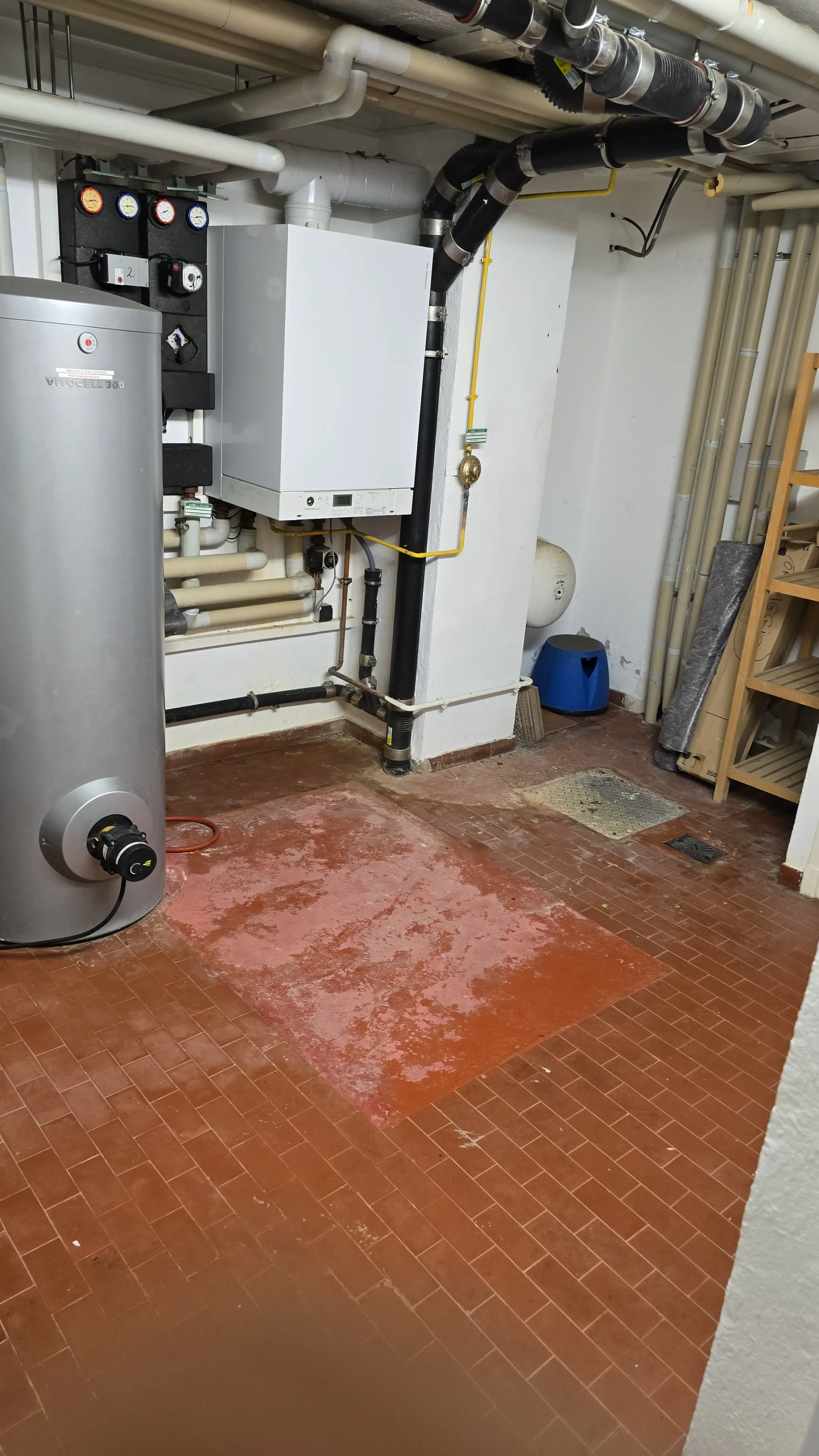 Salle de plomberie avec chauffe-eau et installations visibles au sol