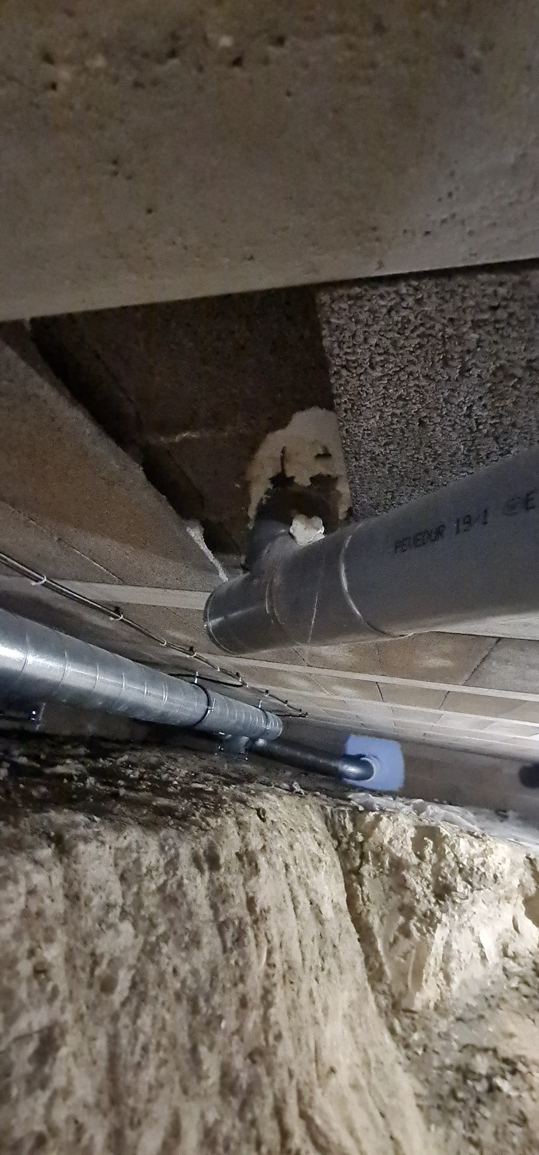 Détails de la plomberie avec des tuyaux en PVC sous une structure en béton